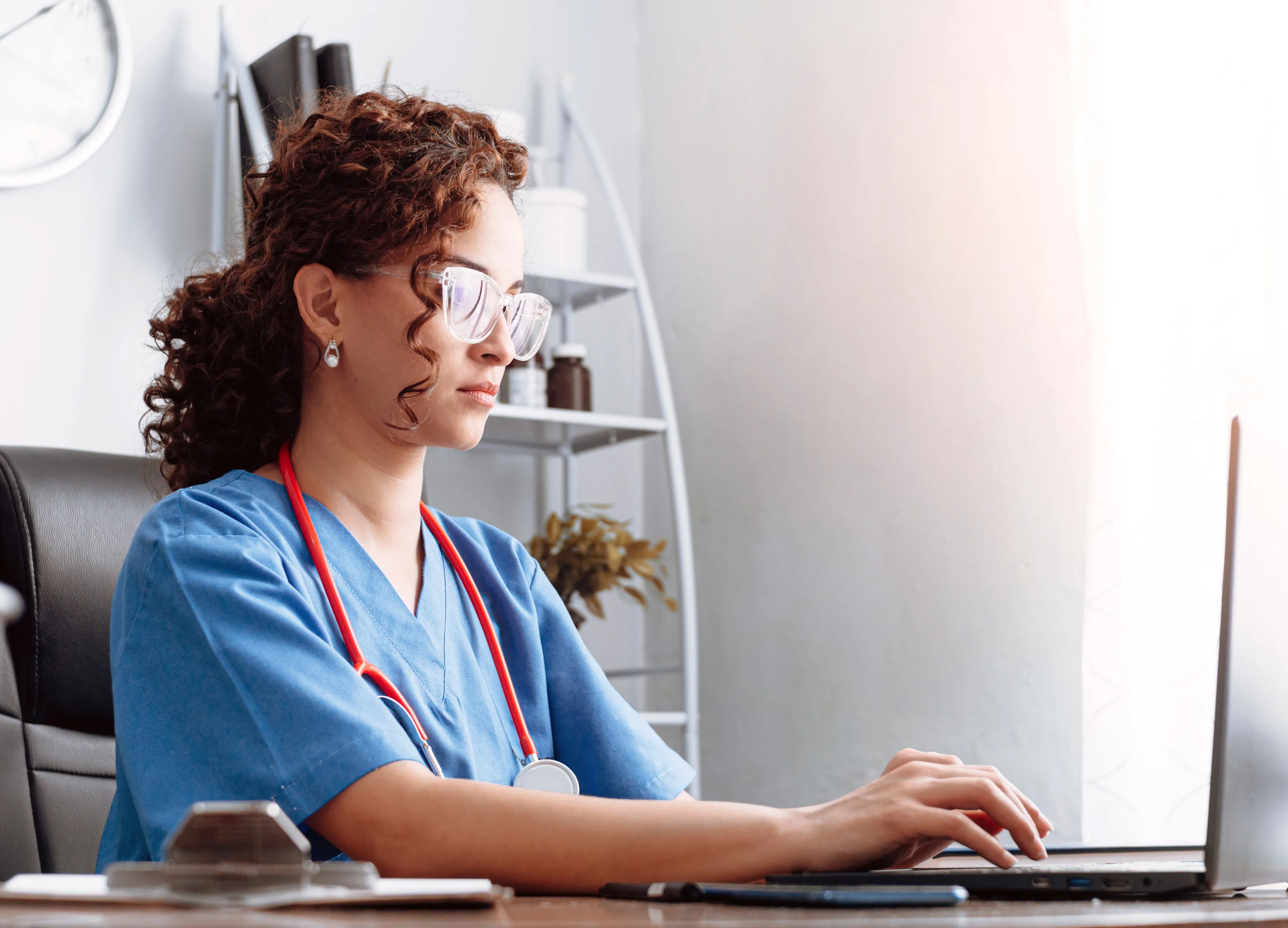 A nurse types on a laptop