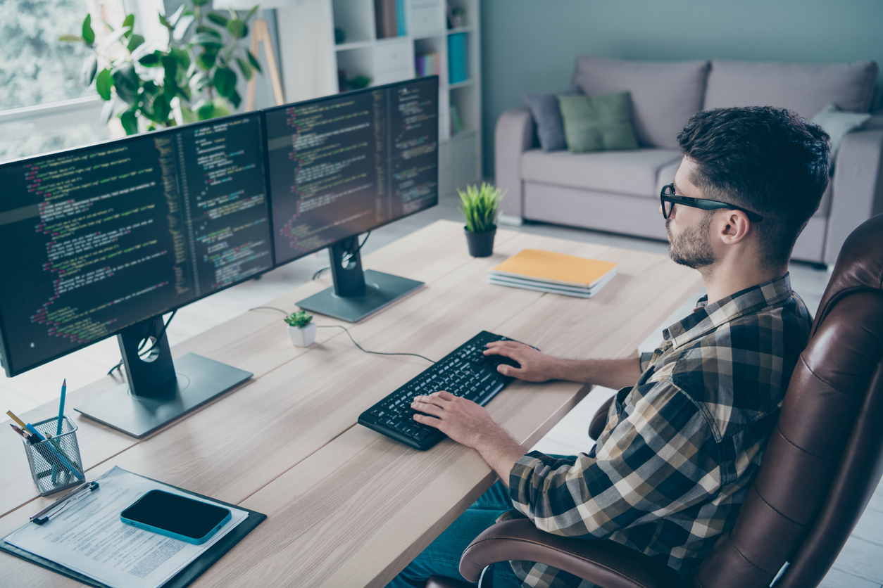 An Information Security Analyst Reviews Code on a Pair of Monitors