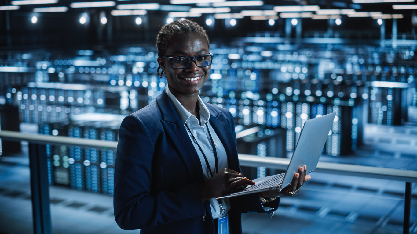 Cybersecurity Specialist Holds a Laptop While Working in a Data Center.