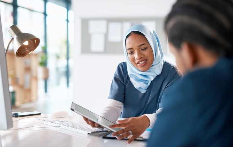 Nurse with a tablet speaking to another health care professional.