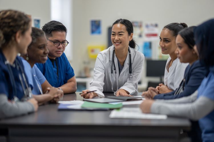 A director of nursing meets with a team at a conference table. 