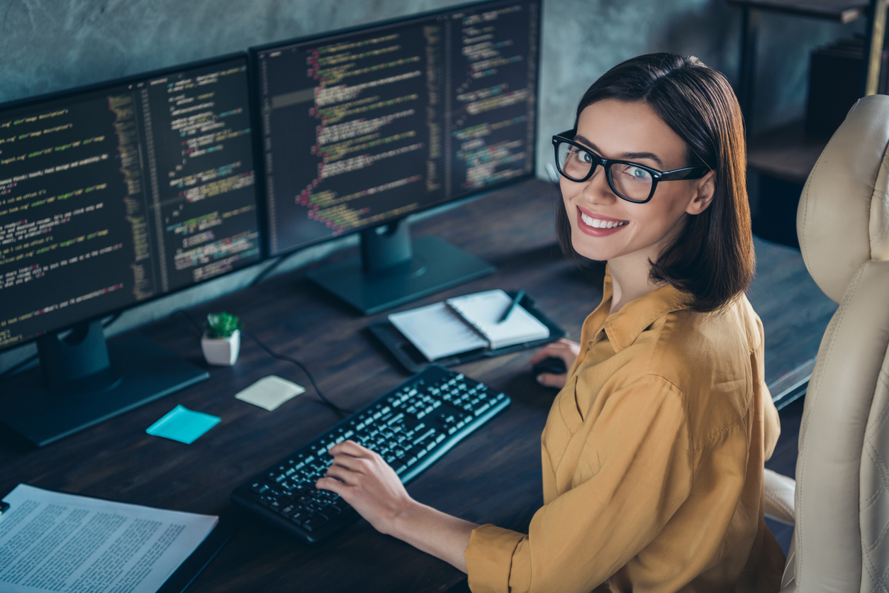A cybersecurity professional sitting in front of two computer monitors.