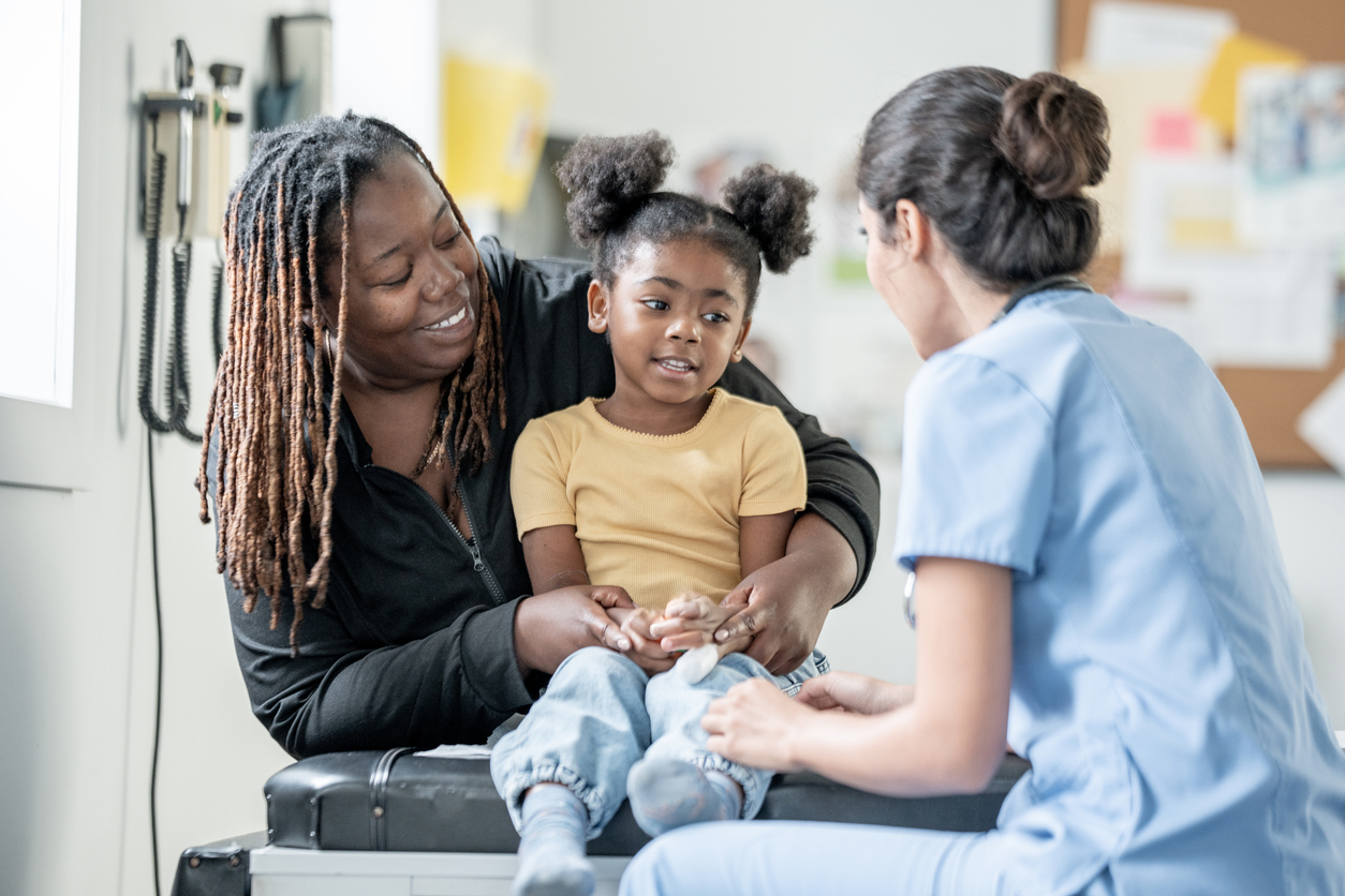 A family nurse practitioner talks with a child and her mother before an examination. 