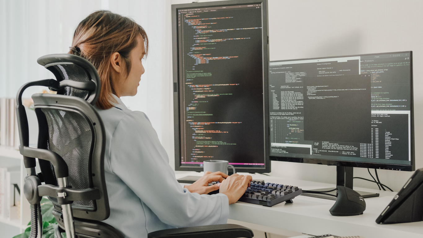 A Penetration Tester Reviews Code on a Pair of Desktop Monitors.