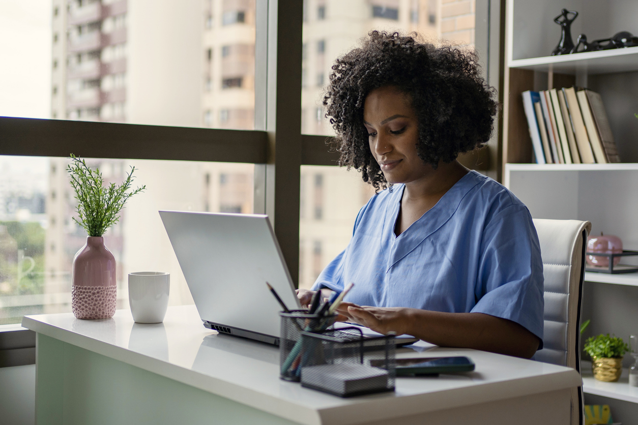 A Nurse Works on a Laptop in an Office
