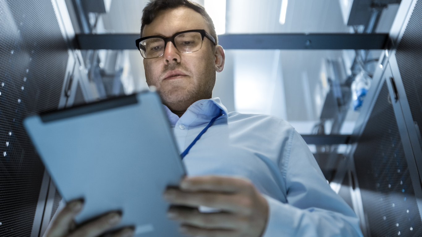 A Cybersecurity Professional Works in a Data Center in a Row of Server Racks.