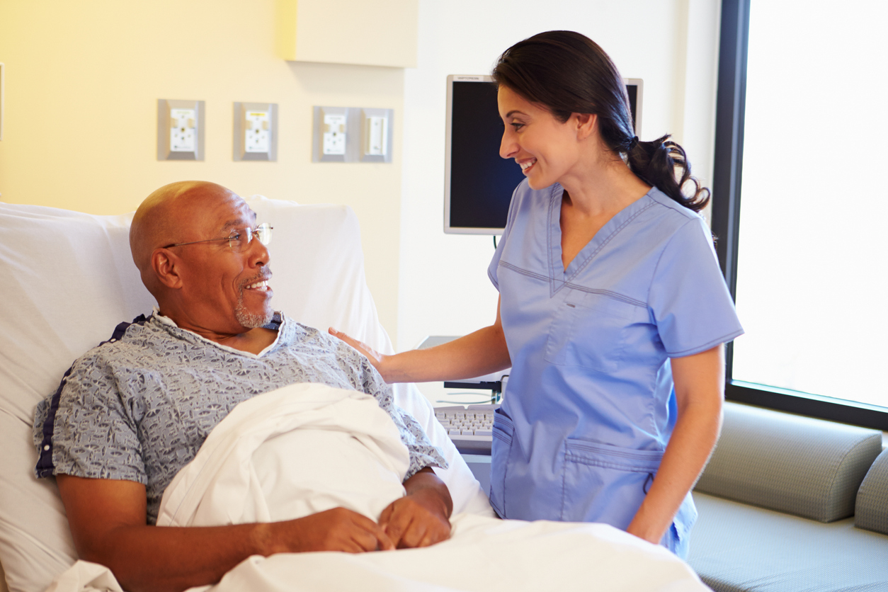Nurse talking to a patient in a hospital bed.