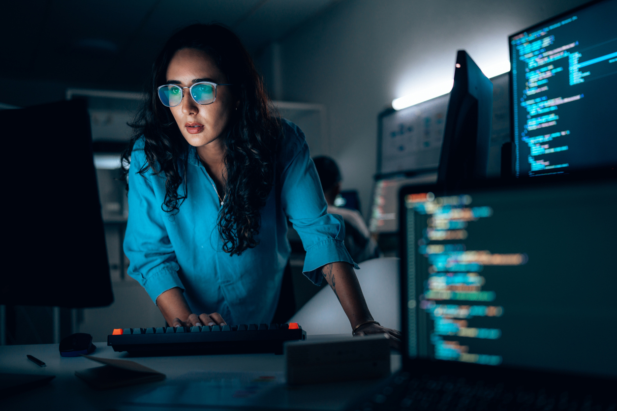 A cybersecurity professional working on multiple monitors.