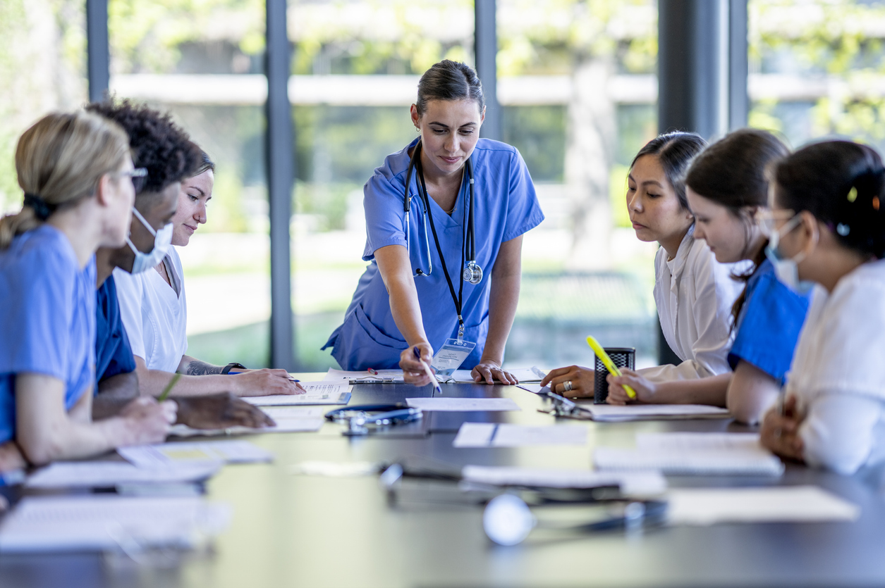 A Nurse Leader Heads a Meeting of Caregivers Seated Around a Conference Table..jpg