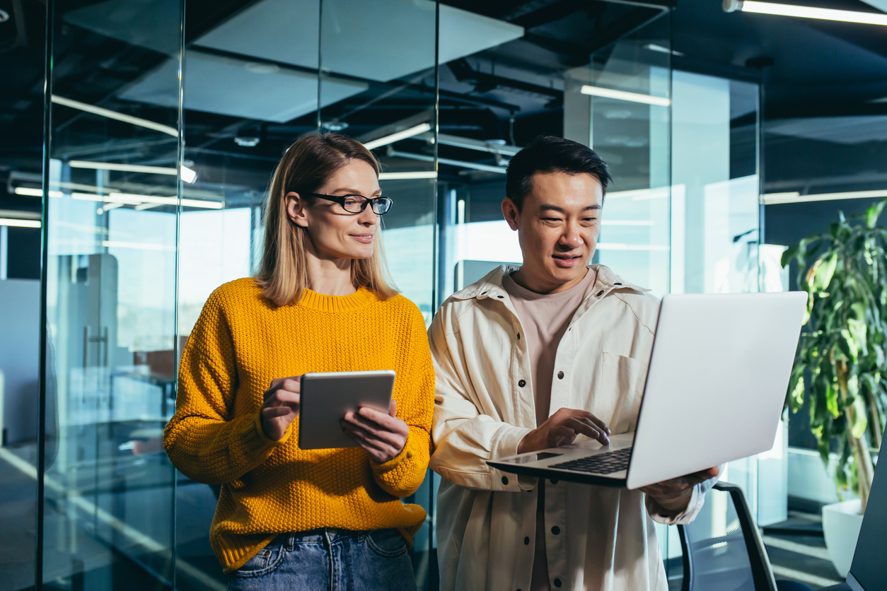 Two cybersecurity professionals standing together looking at their devices.